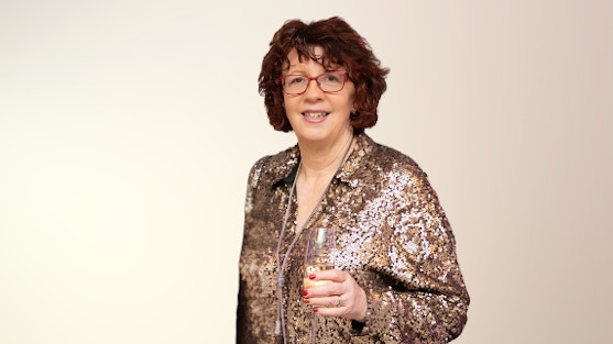 A picture of Sarah, a volunteer with Forward Carers, holding a glass of champagne at a celebration event.