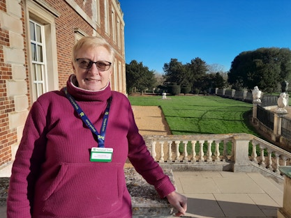 Claire Edwards Volunteer for Wimpole outside the house on a sunny day with a view over the garden