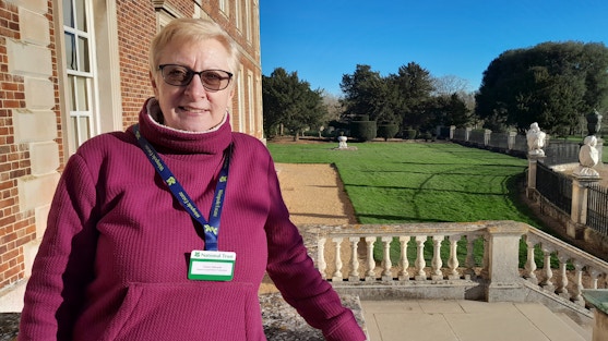Claire Edwards Volunteer for Wimpole outside the house on a sunny day with a view over the garden