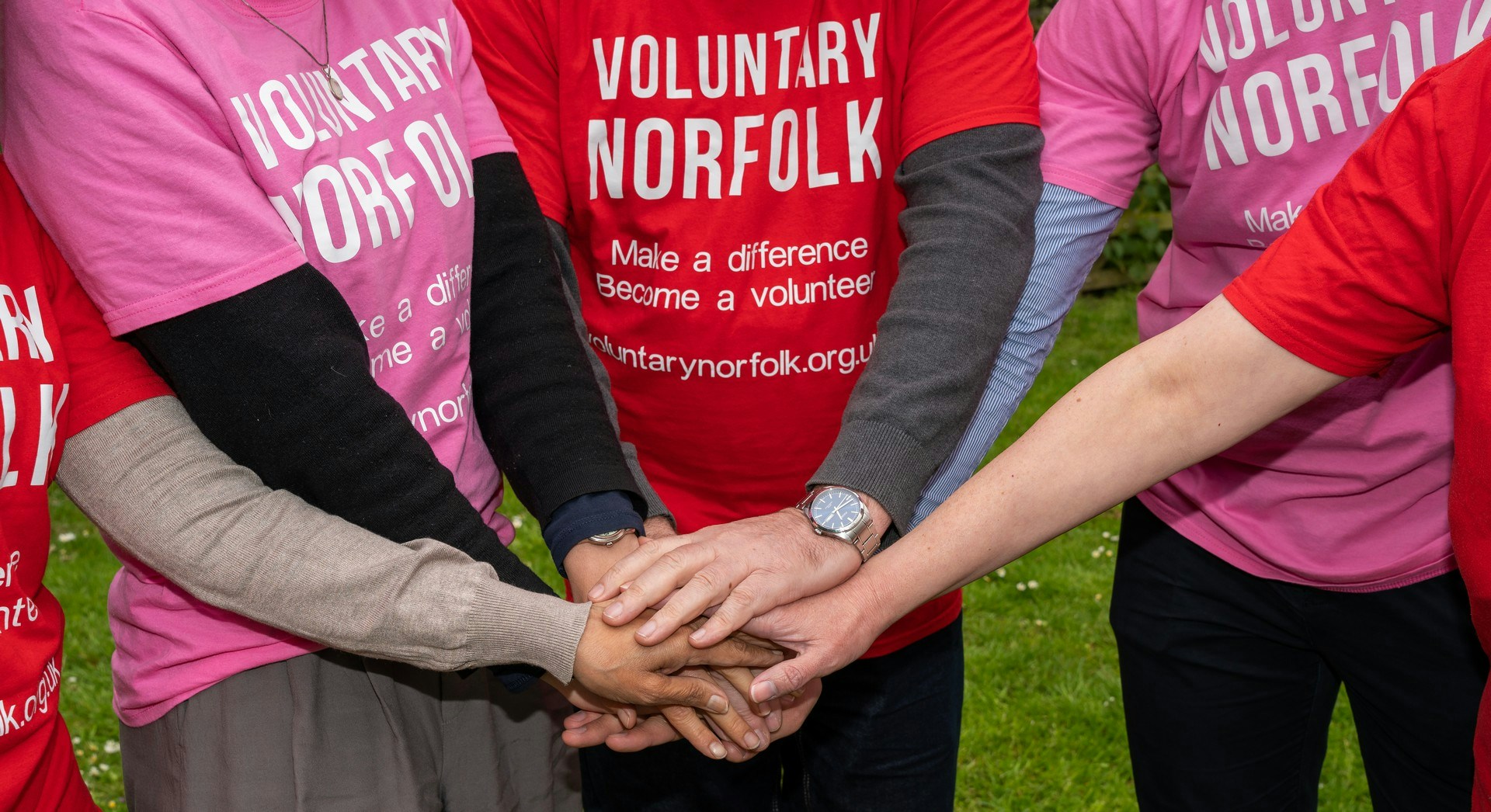 People wearing Voluntary Norfolk T-shirts stacking hands on top of each other