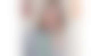 The photo shows Hannah smiling, she has brown shoulder length hair and is wearing a striped black and white top and a green lanyard.