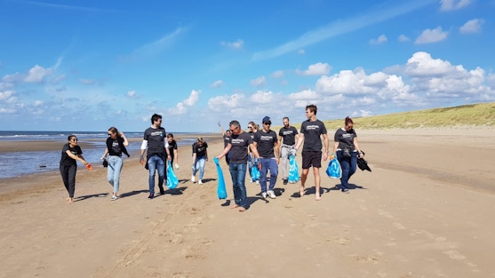 team corporate vrijwilligers zijn vuilnis aan het oprapen op het strand