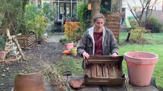 Vrouw met benodigdheden voor het maken van een egelhuis in haar tuin